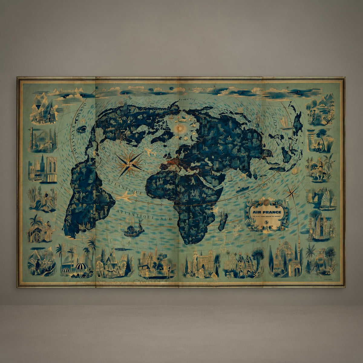 A vintage-style world map print with dark blue landmasses and a pale blue-green ocean background, featuring decorative coastal illustrations and a small cartouche labeled 'Air France.' The print is mounted or photographed against a plain light gray wall.