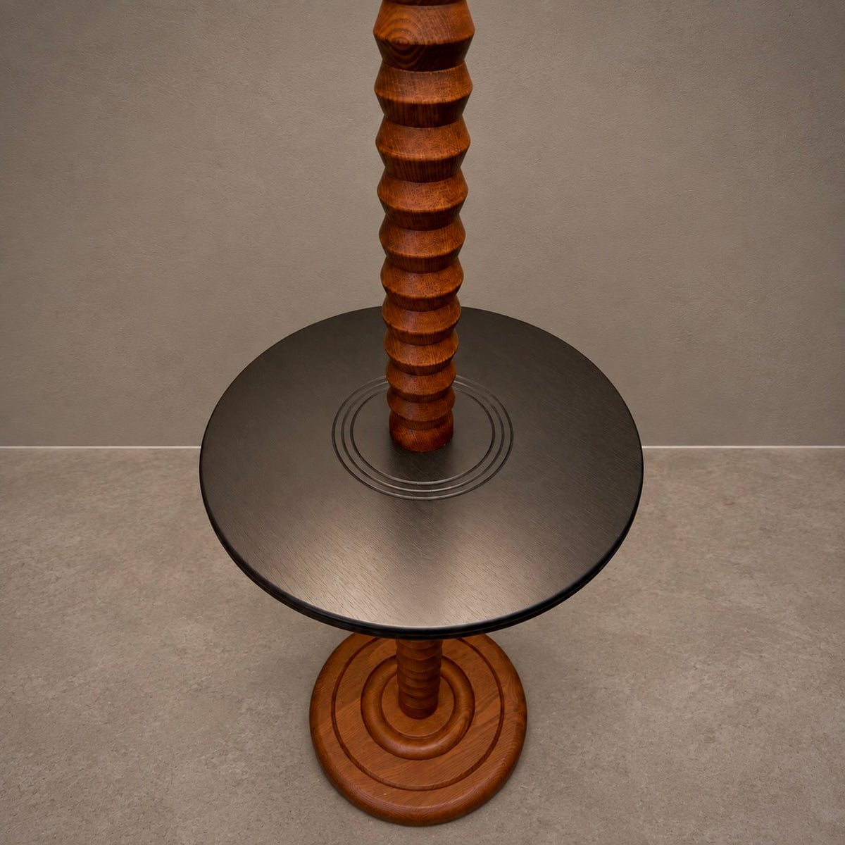 A modern wooden table featuring a round brushed metal top with a central ribbed wooden pedestal and a matching round wooden base, set against a neutral gray background.