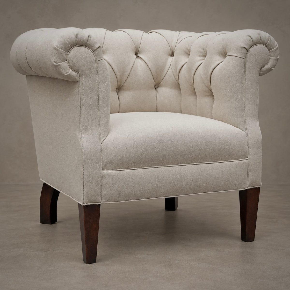 A classic Chesterfield armchair upholstered in cream-colored fabric with dark brown wooden legs, set against a neutral textured gray background.