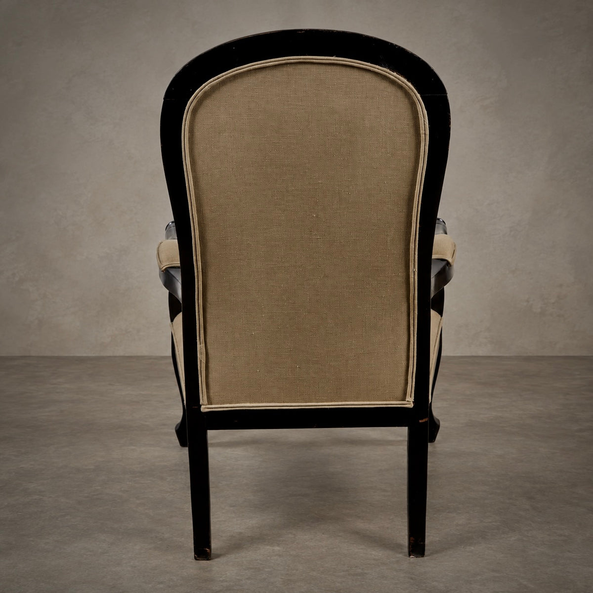 A classic high-back armchair with a black wooden frame and beige linen upholstery, photographed from the back against a textured gray studio backdrop.