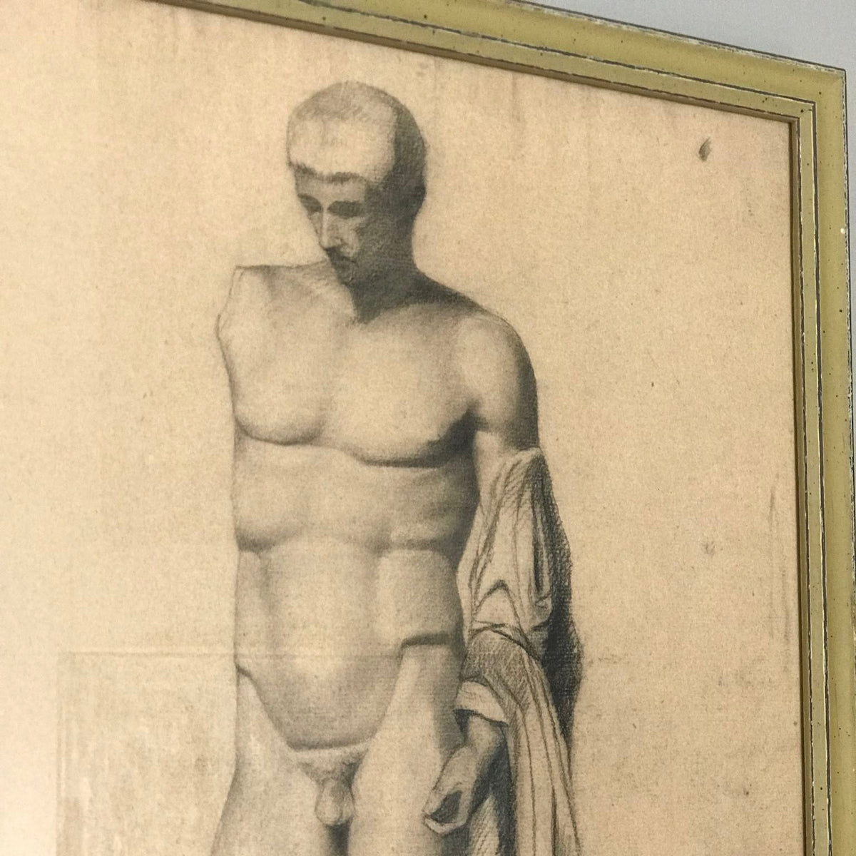 Close up of 19th-century academic charcoal drawing of a standing male nude with drapery, presented in a giltwood frame.