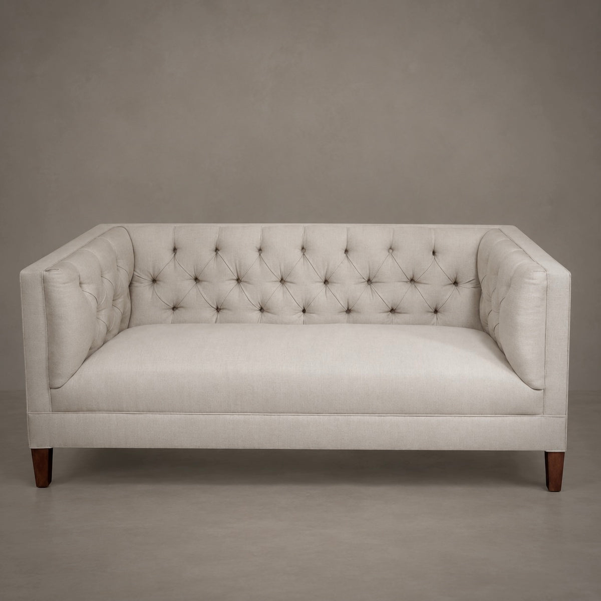 A cream-colored upholstered loveseat with a tufted button-back design, square arms, and dark wood legs, set against a neutral gray studio background.