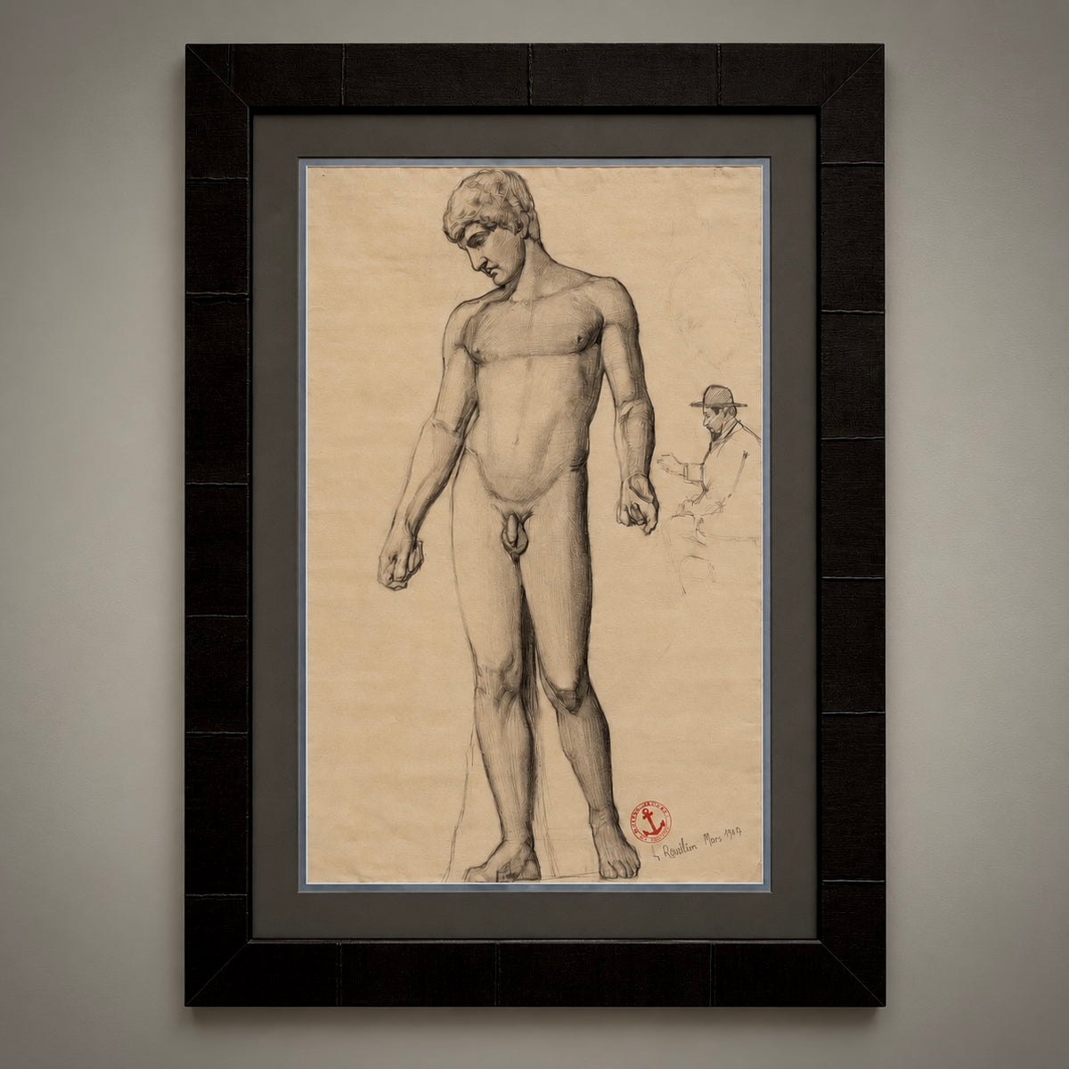 A framed art print featuring a sepia-toned figure drawing on aged beige paper, mounted with a dark gray mat and a textured black frame against a neutral gray wall.