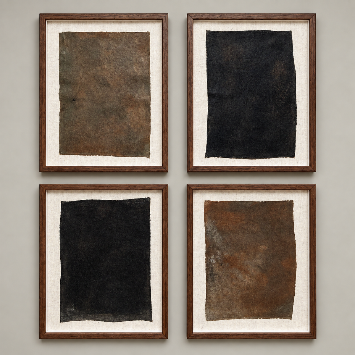 Four framed abstract art prints arranged in a 2x2 grid on a light gray wall. Each print features textured rectangular panels in earthy tones of brown, black, and rust orange, set within white matting and dark wood frames.