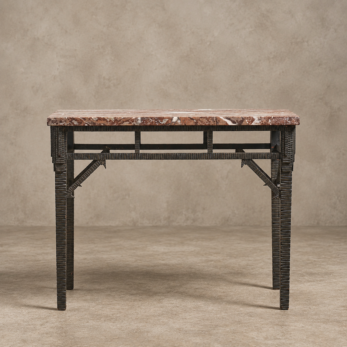 A console table featuring a rectangular reddish-brown marble top and a dark woven rattan frame with geometric metal support brackets, set against a textured beige studio backdrop.