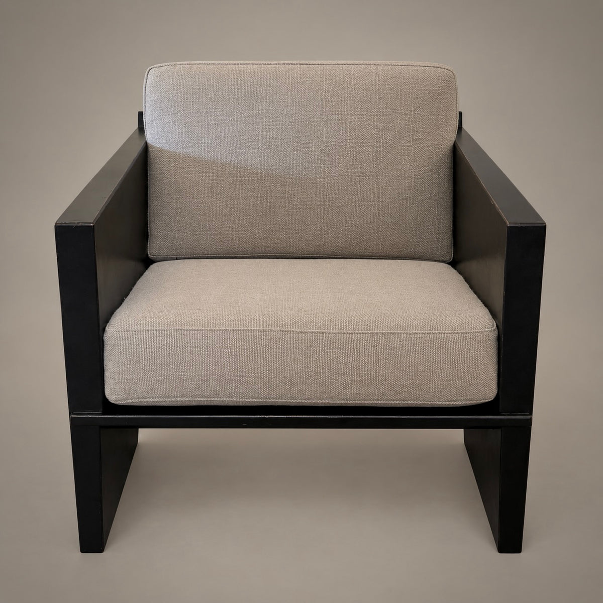 A modern outdoor armchair with a black frame and thick, textured light beige fabric cushions on the seat and backrest, shown against a solid neutral background.