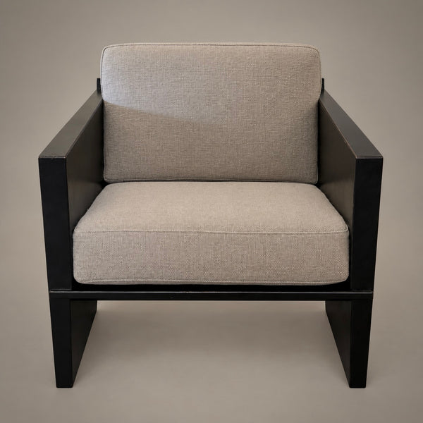 A modern outdoor armchair with a black frame and thick, textured light beige fabric cushions on the seat and backrest, shown against a solid neutral background.