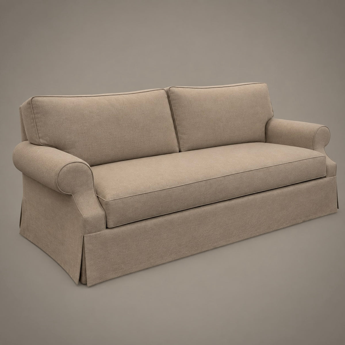 A beige upholstered sofa with rolled arms, two back cushions, and a skirted base, shown on a plain warm gray studio background.