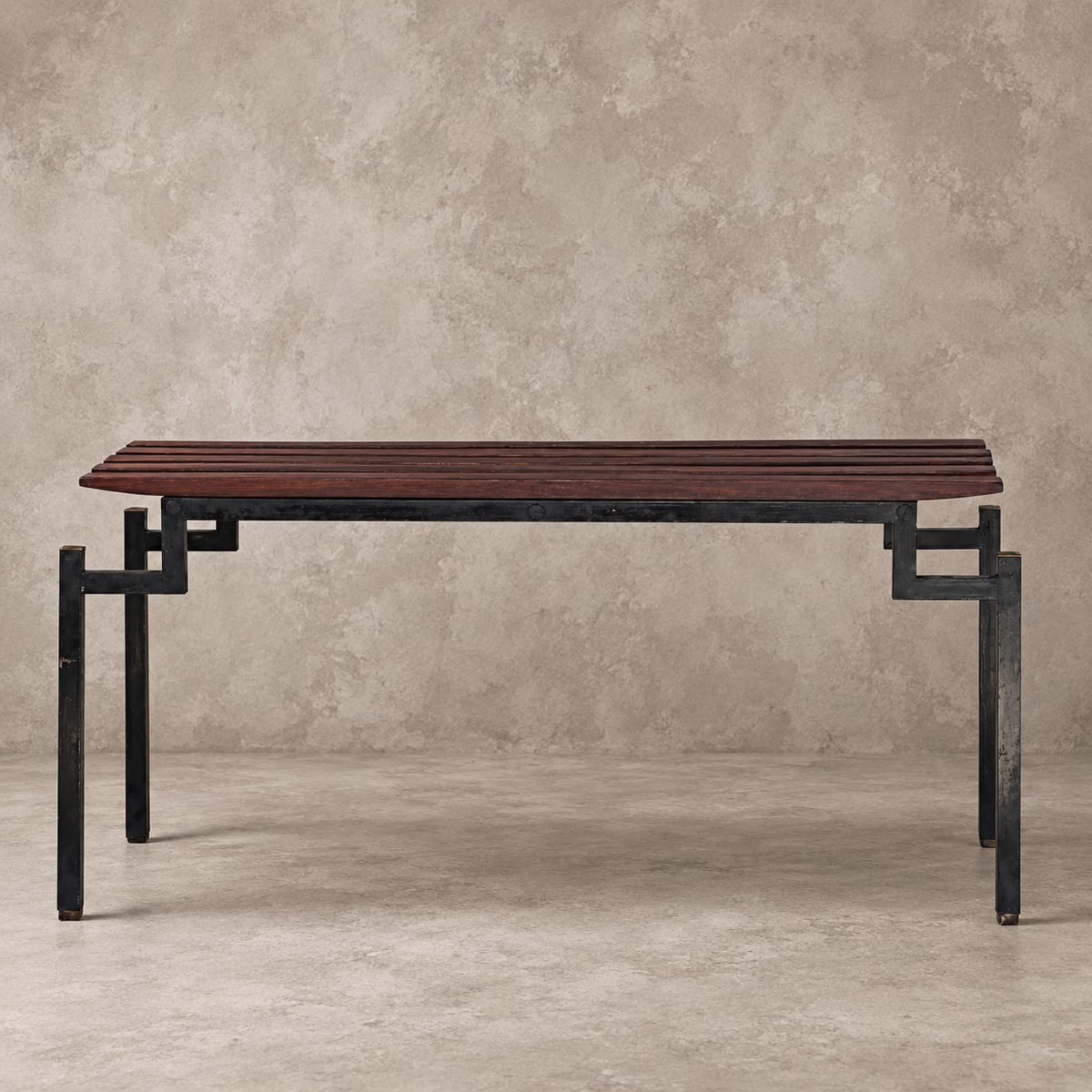 A rectangular wooden console table with a dark reddish-brown slatted top and a black metal frame with geometric legs, set against a textured beige wall and concrete floor.