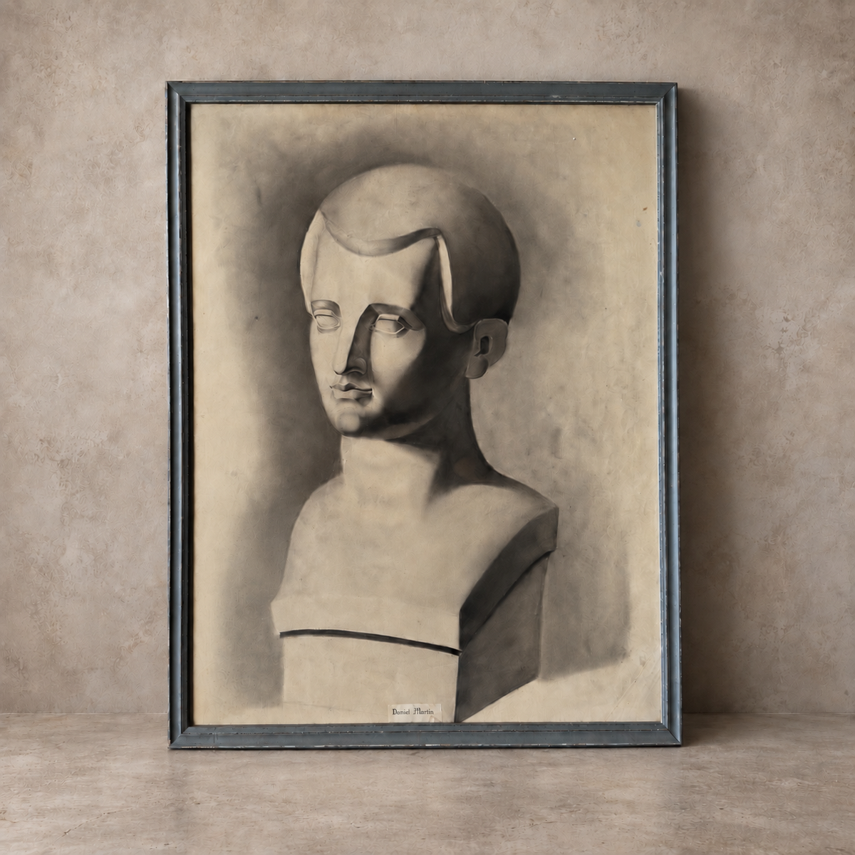 A framed monochrome art print depicting a stylized bust sculpture, leaning against a textured beige wall on a matching surface.