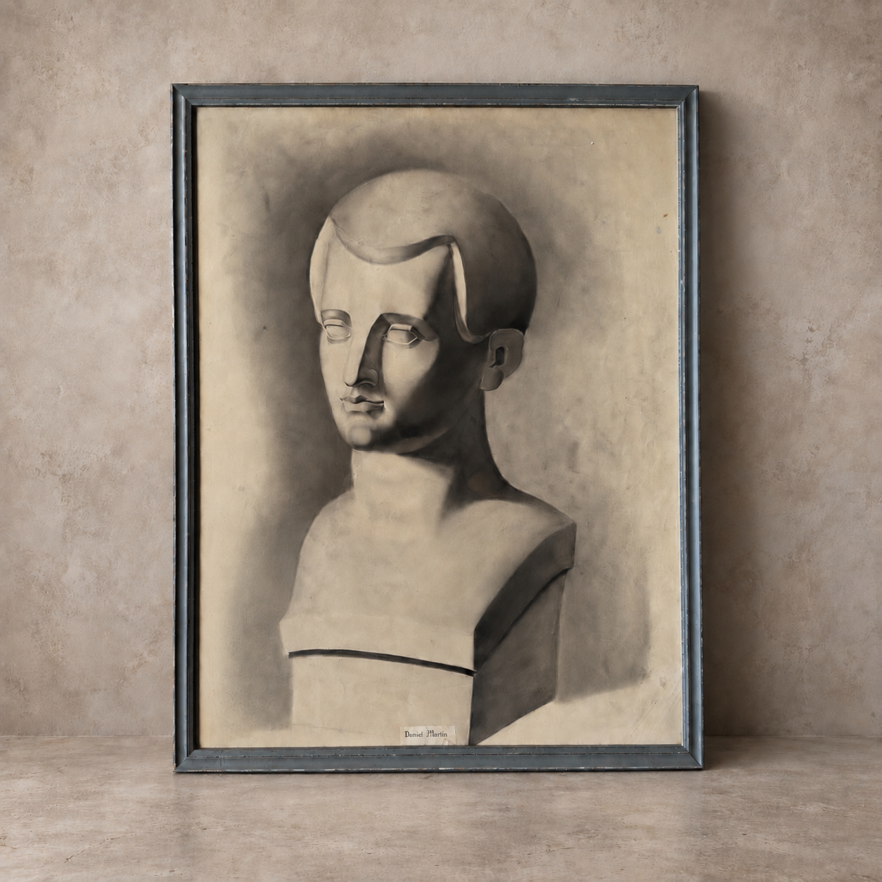 A framed monochrome art print depicting a stylized bust sculpture, leaning against a textured beige wall on a matching surface.