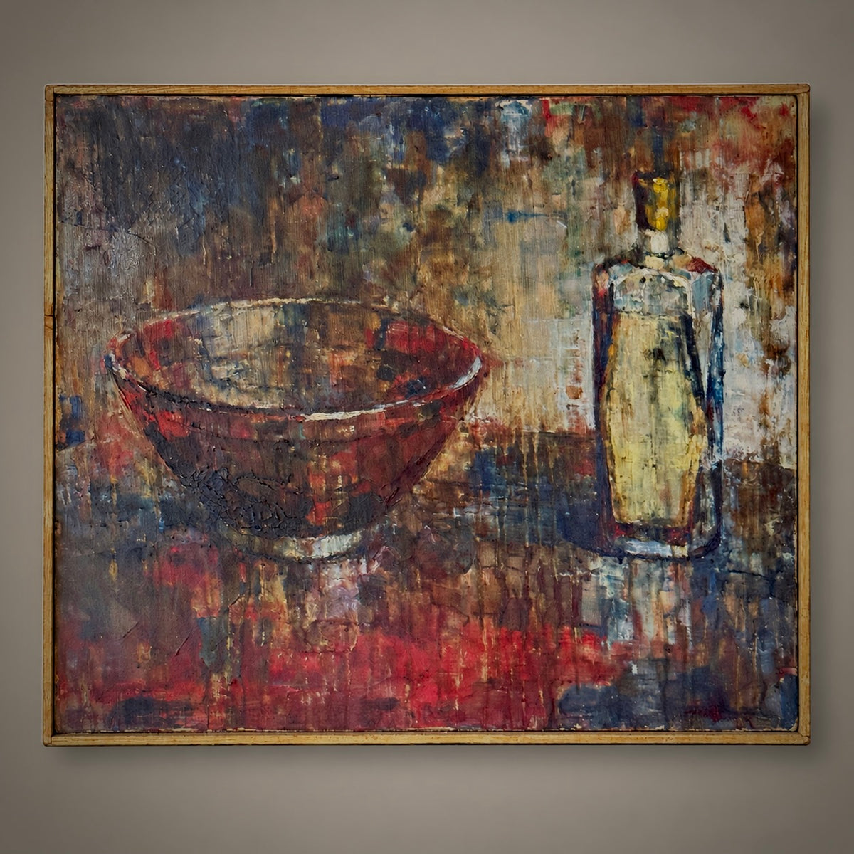 An abstract still life painting on canvas featuring a textured red bowl and a cream-colored bottle, enclosed in a thin gold frame and displayed on a neutral gray wall.