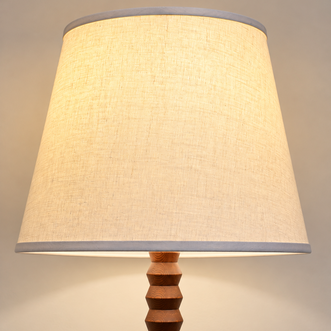 A linen shade mounted on an oak turned floor lamp nase