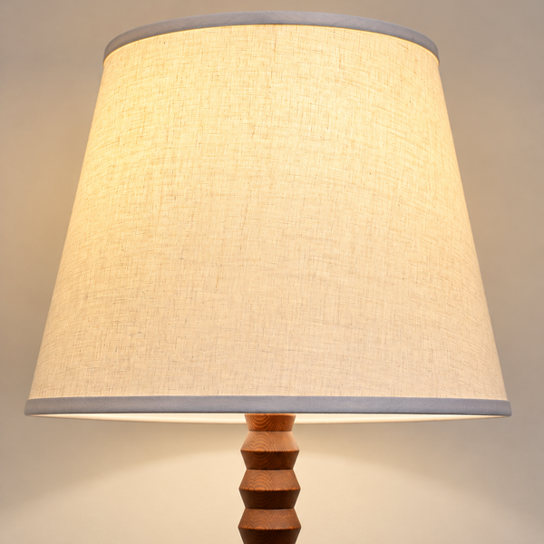 A linen shade mounted on an oak turned floor lamp nase