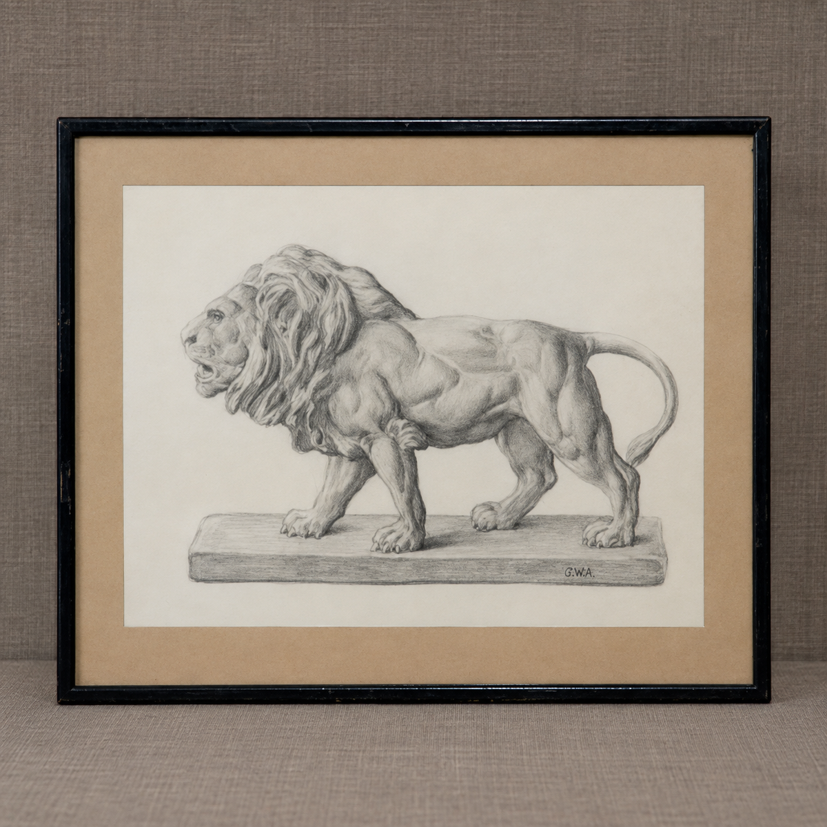 A framed black and white pencil drawing of a muscular lion standing on a pedestal, set against a beige mat and a black frame, displayed on a textured gray surface.