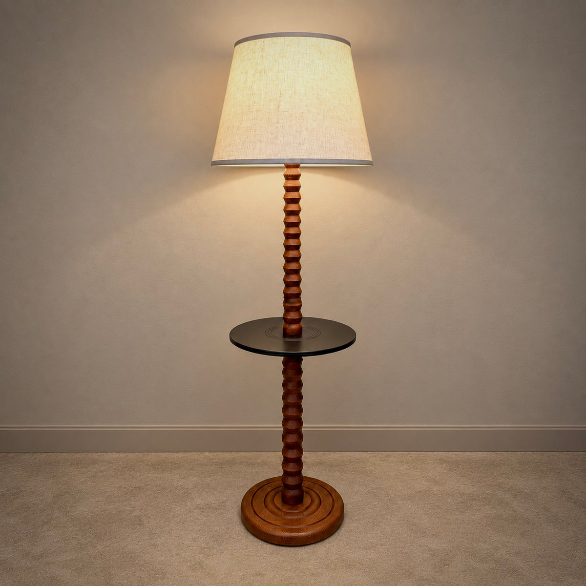 A vintage-style floor lamp with a ribbed wooden pole, a small round glass side table, and a tapered beige fabric shade, shown lit against a neutral wall and carpet.