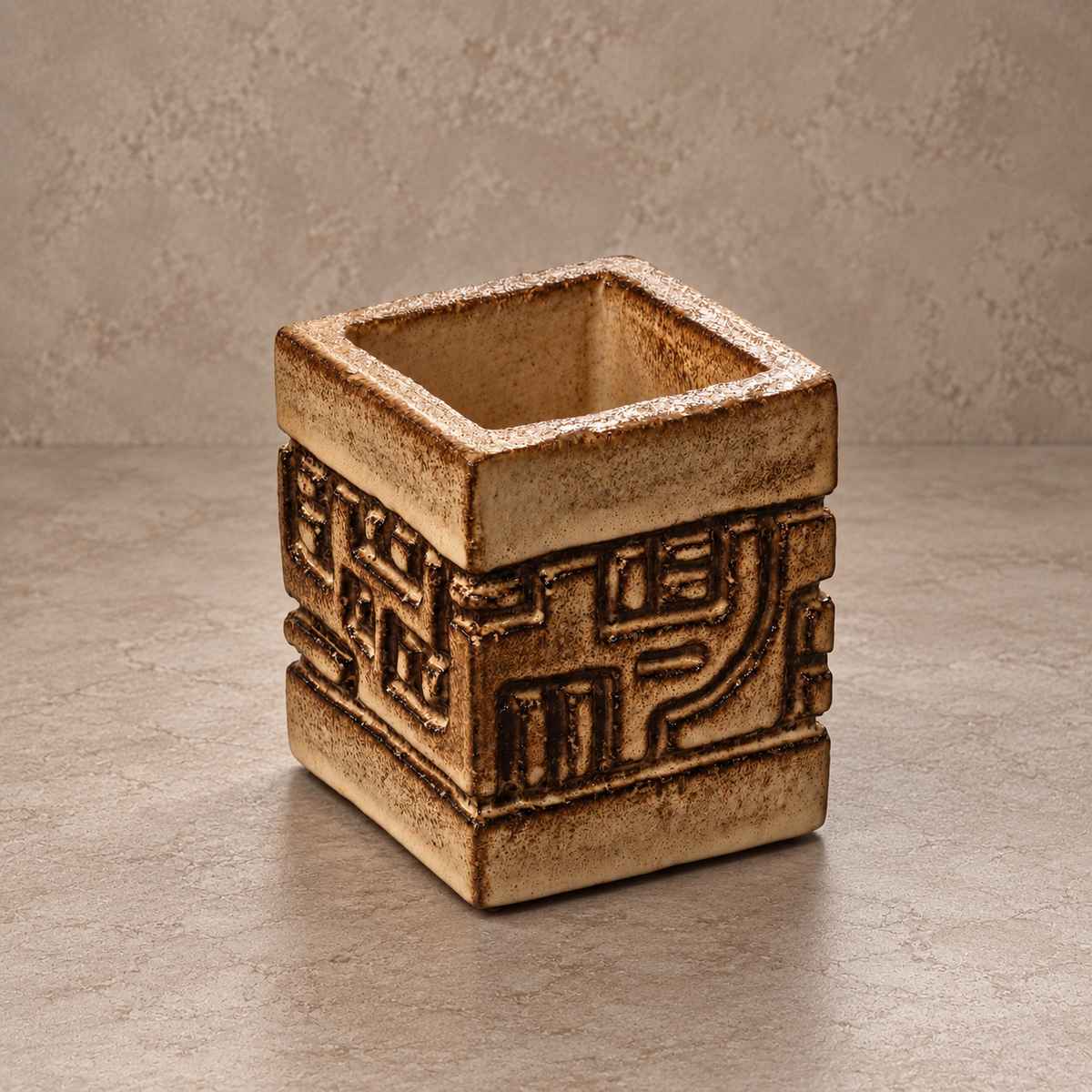 A square ceramic planter with a rustic, textured finish and embossed geometric patterns, set against a neutral beige background.