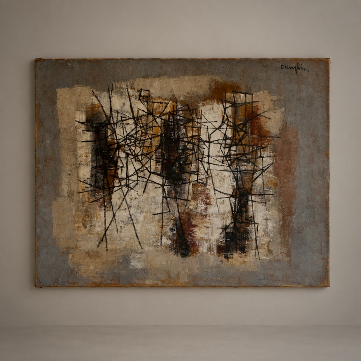 An abstract expressionist painting hanging on a neutral gray gallery wall. The artwork features a textured, layered background of beige, brown, and gray tones overlaid with chaotic, energetic black and dark brown scribbled lines.