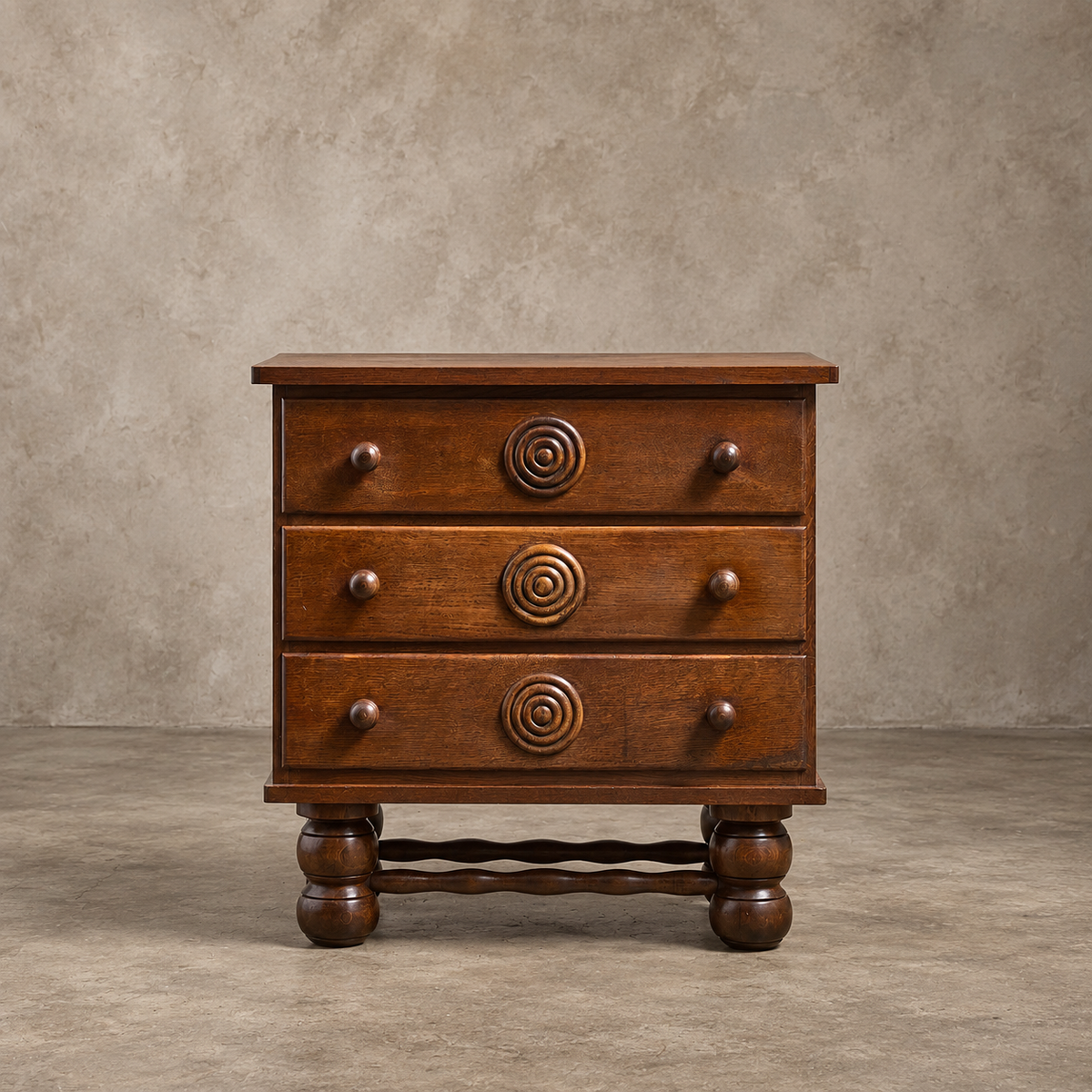 A three-drawer wooden nightstand with a warm medium-brown finish, featuring spiral carved drawer pulls and turned ball legs, set against a textured beige studio backdrop.