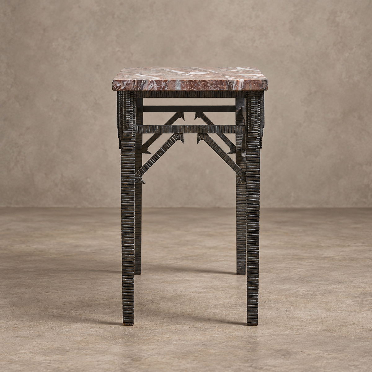 A small console table featuring a reddish-brown marble top and a dark, textured woven metal frame with geometric support beams.