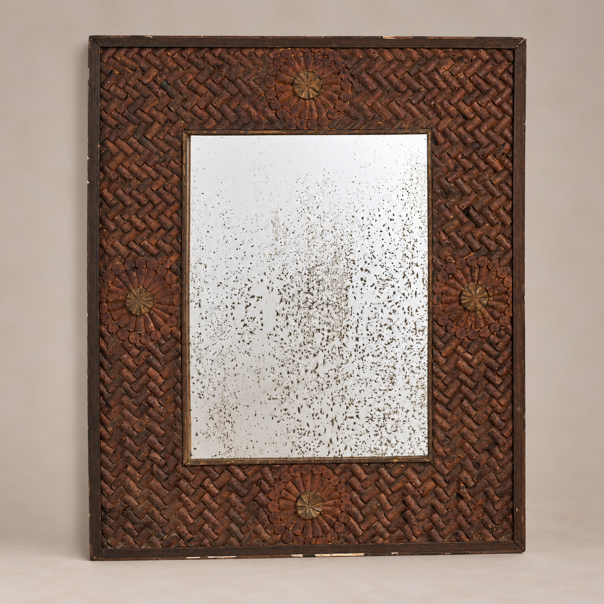 A rectangular wall mirror with a dark brown woven rattan frame and decorative starburst medallions in the corners, set against a neutral beige background.