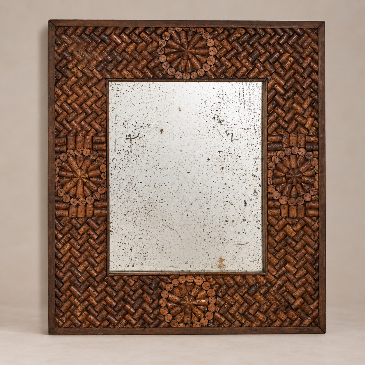 A square decorative mirror with a dark brown woven wood frame featuring intricate geometric patterns and floral motifs around a distressed silver mirror center.