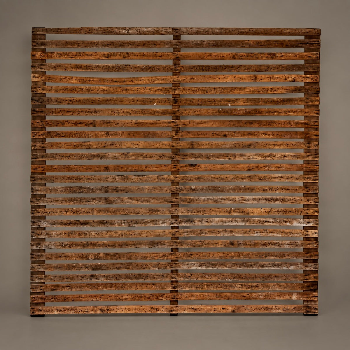 A square wooden wall art piece featuring a rustic slatted design with horizontal weathered wood bars in warm brown and orange tones, displayed against a neutral gray background.