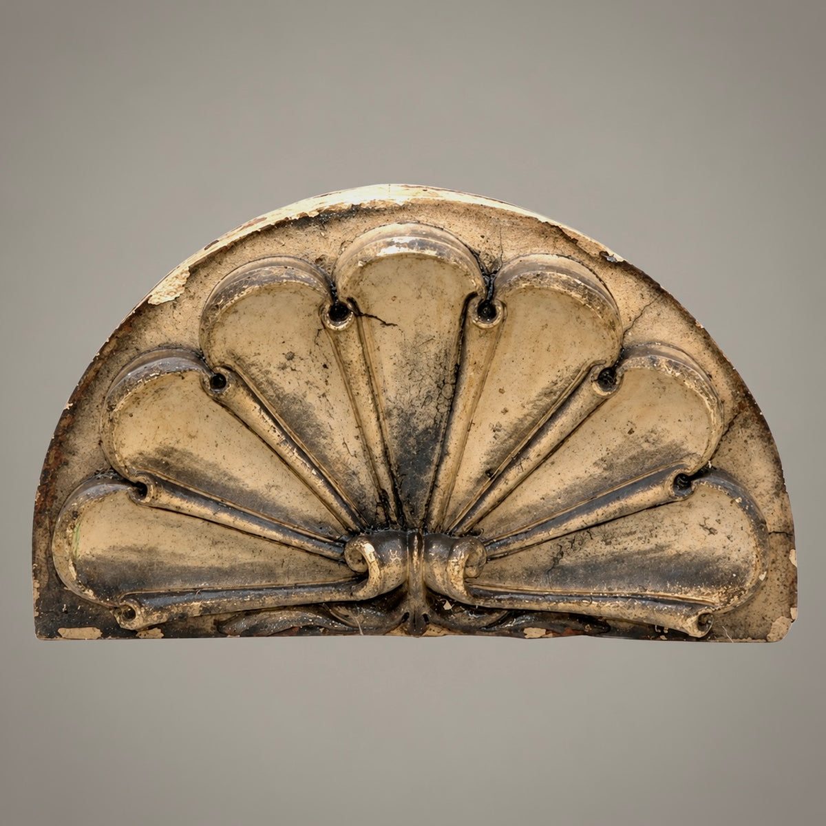 An antique decorative plaster or stone architectural mold in a fan or shell-like segmented design, shown against a neutral gray background.