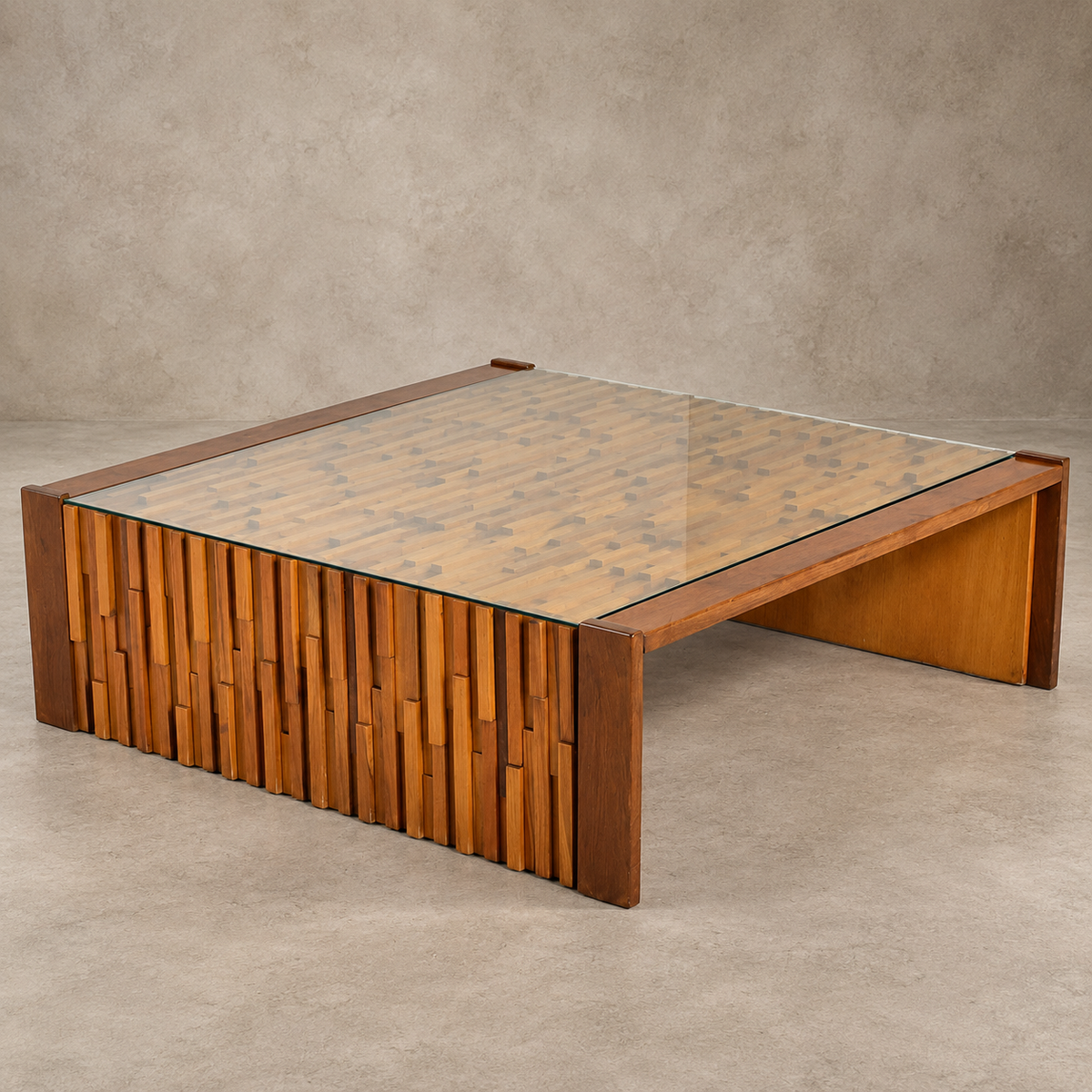 A modern low coffee table with a glass top, featuring a warm wood frame and a front panel made of vertically aligned wooden slats in varying tones, set against a textured concrete background.