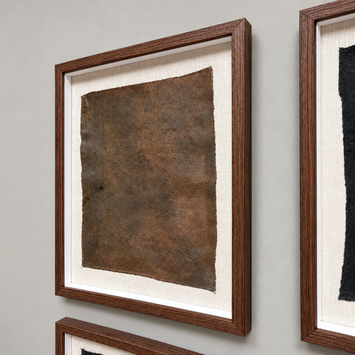 A framed abstract art print featuring a textured brown square on a cream mat, housed in a dark brown wooden frame, mounted on a light gray wall.