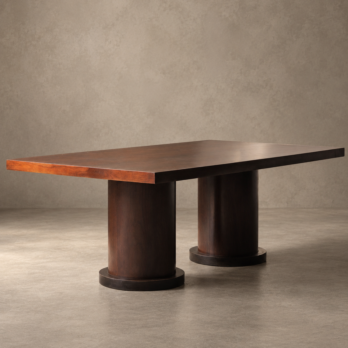 A rectangular wooden dining table with a dark brown top and cylindrical pedestal legs, set against a textured gray studio background.