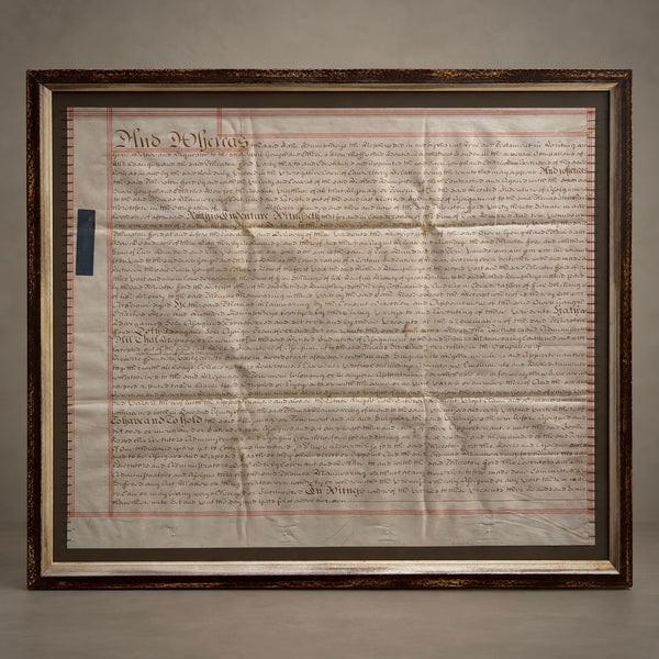 A framed property deed, featuring the original parchment document inside a large, ornate dark brown wooden frame.
