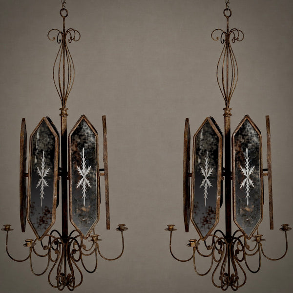 A pair of vintage-style multi-light chandeliers with distressed bronze metal frames and mirrored glass panels featuring white snowflake designs, set against a solid taupe background.
