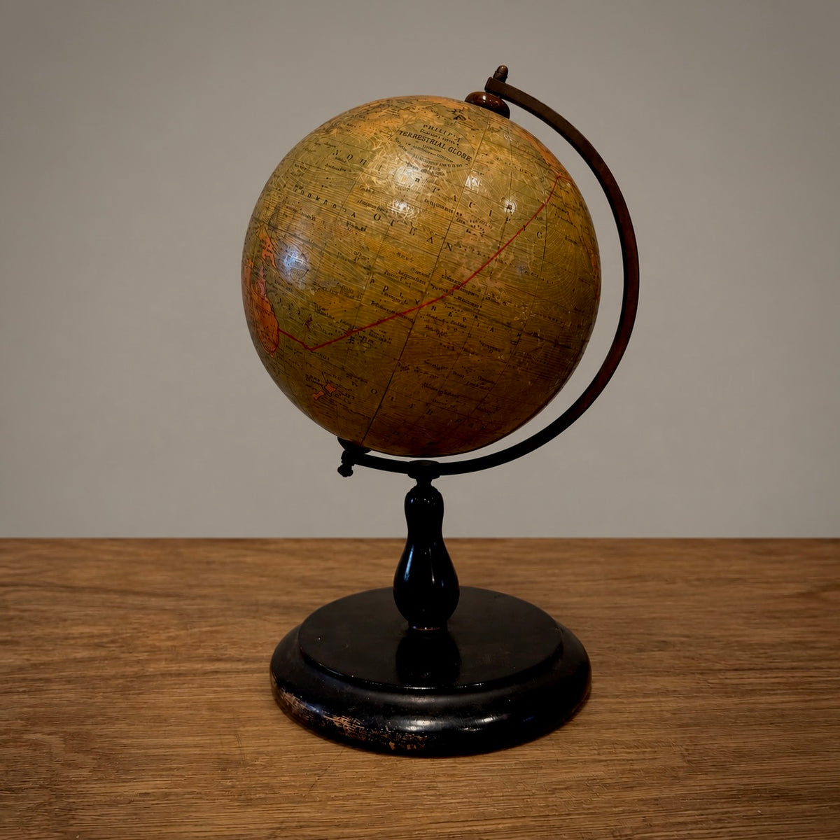A vintage-style globe on a black stand, placed on a wooden tabletop against a plain light gray wall.