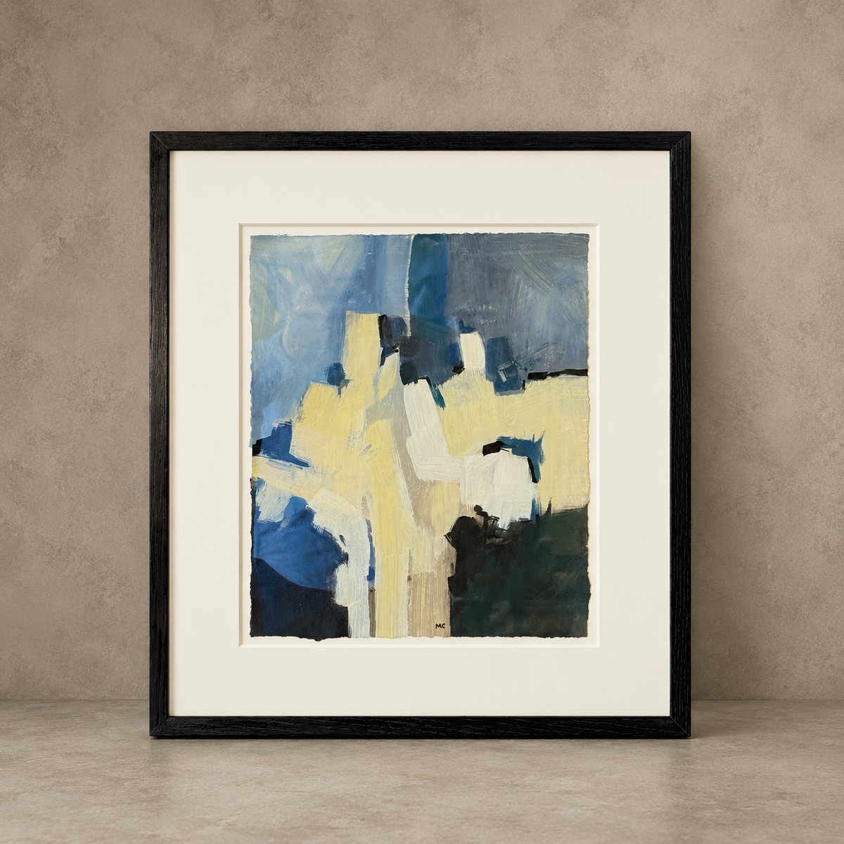 Framed abstract art print with a black frame and white mat, featuring blue, yellow, and cream brushstrokes, displayed against a textured beige wall and floor.