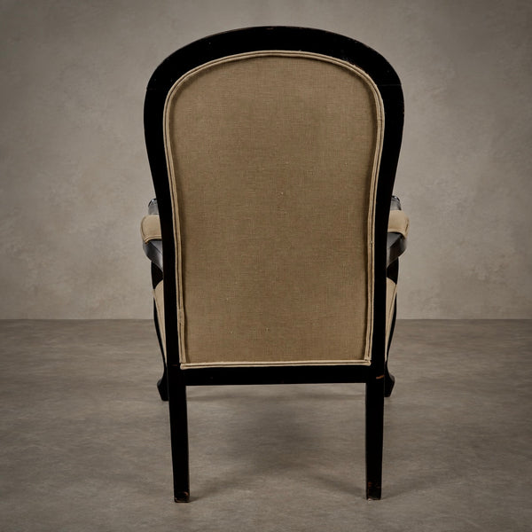 A classic high-back armchair with a black wooden frame and beige linen upholstery, photographed from the back against a textured gray studio backdrop.