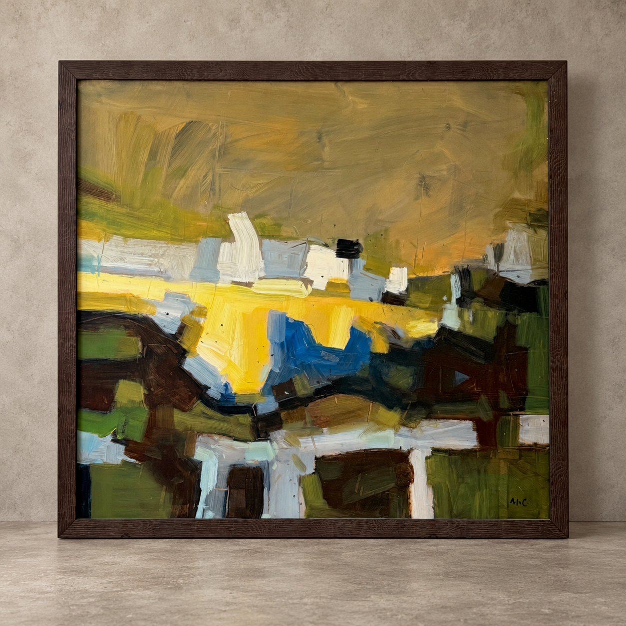A framed abstract landscape painting featuring bold brushstrokes of yellow, green, brown, blue, and white, housed in a dark rustic wooden frame and displayed against a textured gray wall.