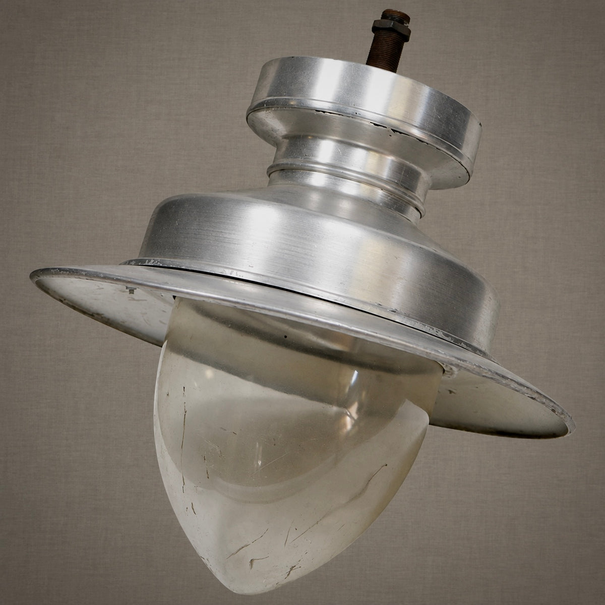 A vintage industrial-style metal light fixture with a brushed silver aluminum shade and a frosted white glass globe, shown against a neutral textured gray background.