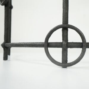 Close-up of a dark cast iron decorative stand or frame leg with a circular crossbar design on a white background.