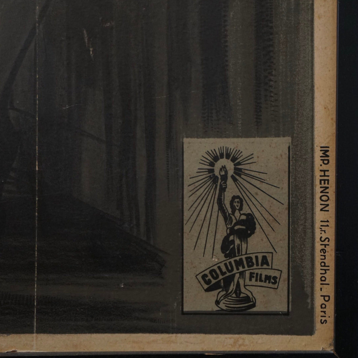 A vintage black-and-white printed card or poster showing a stylized figure holding a light above the words 'COLUMBIA FILMS,' with vertical text along the right edge reading 'IMP. HENON 11.