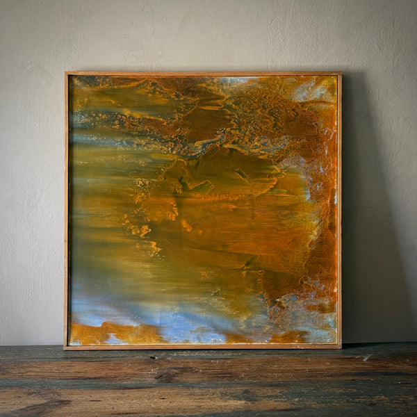 A framed abstract painting by Lucien Beniere, featuring warm earthy colors with intricate patterns, displayed on a wooden surface against a wall.