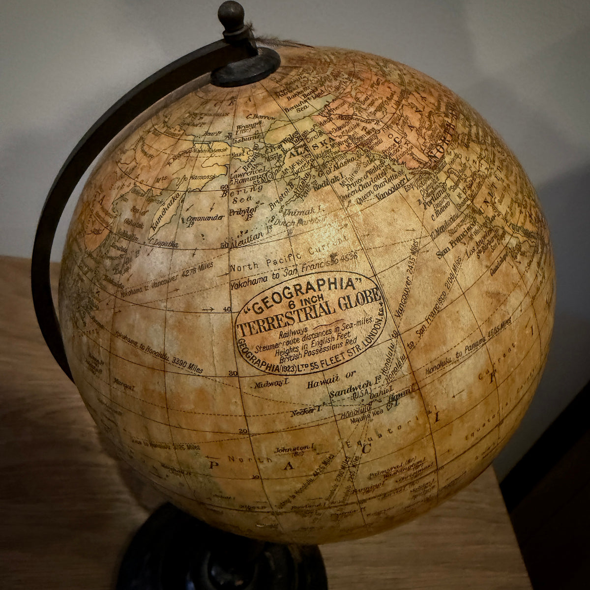 An antique-style globe with a warm tan and brown map surface, featuring the text 'GEOGRAPHIA TERRAE ITALICAE' in the center, mounted on a dark metal stand.