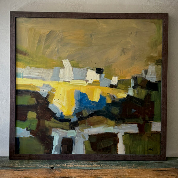 A contemporary abstract framed painting featuring geometric patterns in yellow, blue, and black tones on a wooden floor against a wall.