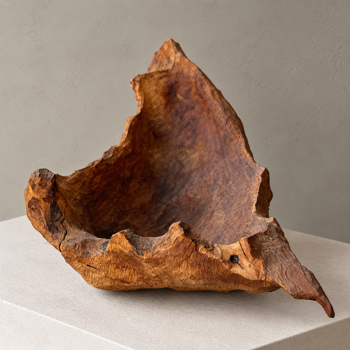 A rustic, organic-shaped wooden bowl made from rough tree bark, displayed on a light beige pedestal against a neutral gray background.
