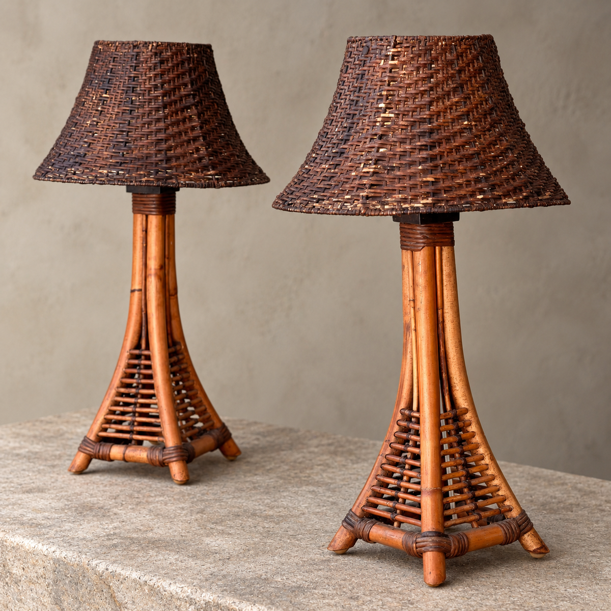 A sculptural pair of vintage bamboo lamps with tripod-style bases and woven shades, against a neutral background. 