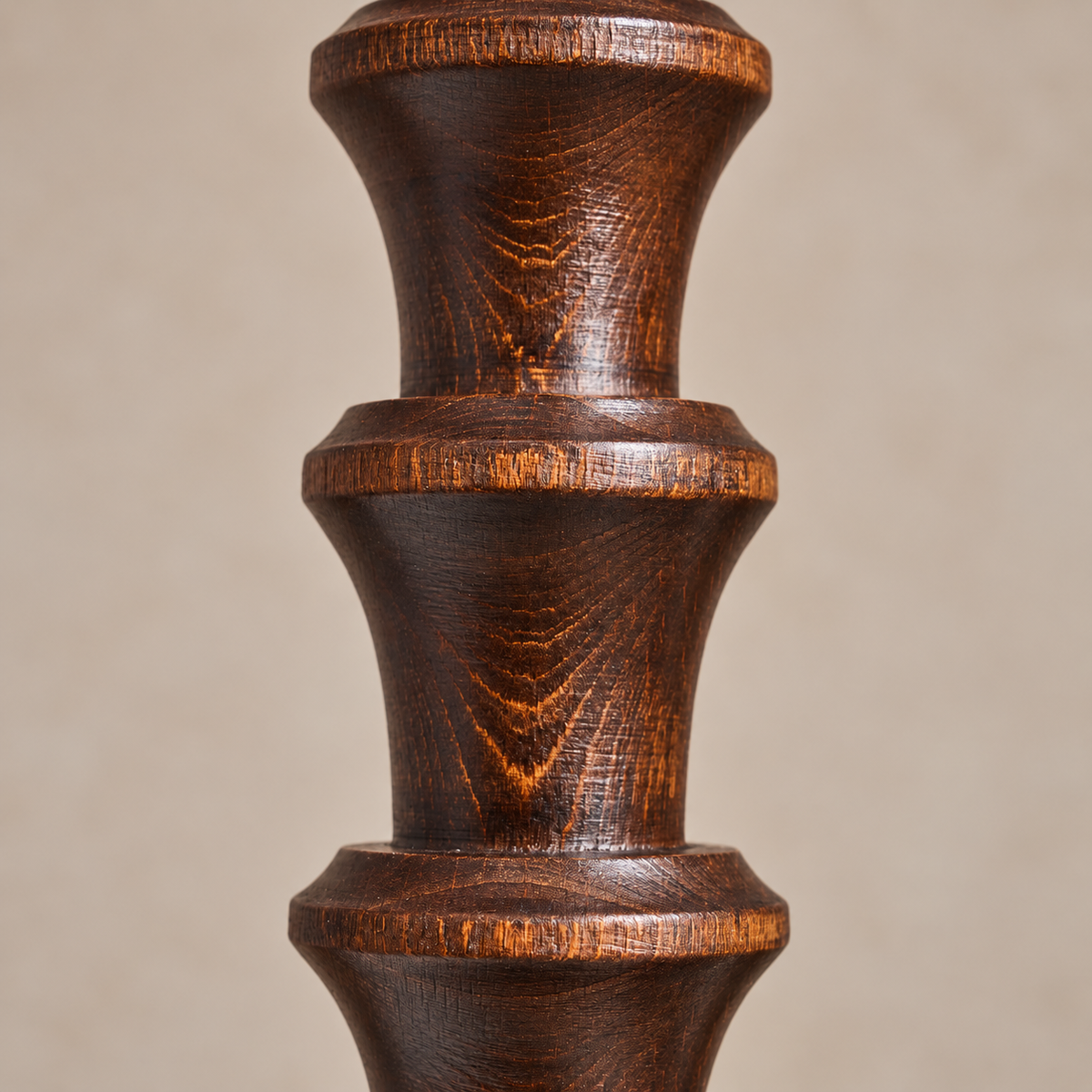 A close-up of a dark brown wooden candlestick with a glossy finish and visible wood grain, set against a plain beige background.