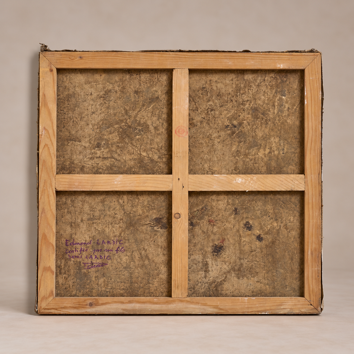 The back of a square wooden framed artwork, showing a light natural wood frame with a four-panel grid and a textured brown canvas or paper surface inside, photographed against a plain beige studio background.
