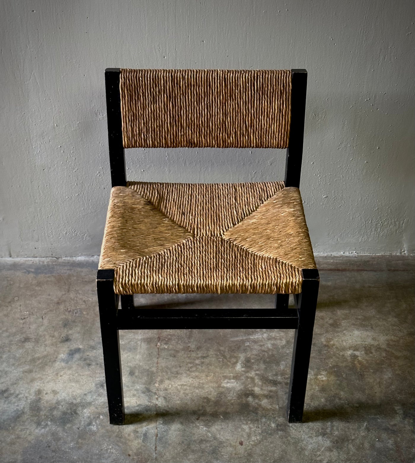 A mid-century modern dining chair with dark wooden frames and a woven rush seat, set against a neutral background.